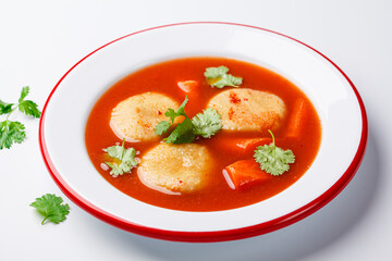 Traditional Jewish tomato soup with matza balls, white background.