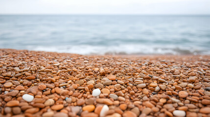 Close-up of smooth, red pebbles on a beach with a blurred ocean background.  Perfect for tranquility, nature, and travel themes.