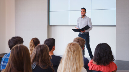 Male Teacher Giving Presentation To High School Or University Class In Front Of Blank Screen
