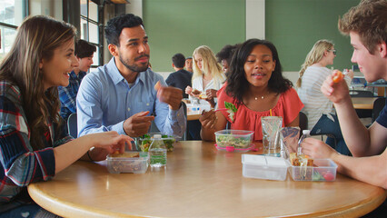 Staff And Students In Cafeteria Of High School College Or University Eating Lunch Together