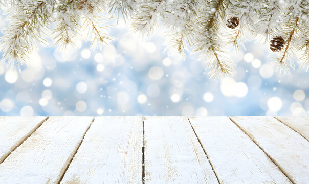 Winter wonderland scene snow-dusted wooden planks, pine branches, and a bokeh background perfect for holiday cards or product displays.