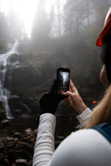 Capturing the Unmatched Beauty of Nature A Hiker with a Smartphone by a Waterfall