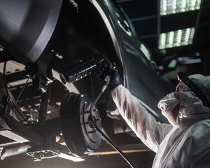 The master sprays an anti-corrosion compound on the bottom of the car. 