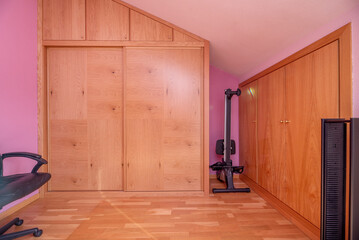 A bedroom in an attic room with custom-made built-in wooden wardrobes