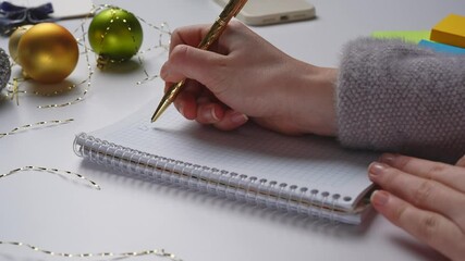 Close up shot of decorated white office desk, woman write in spiral notebook 2025 wish list, wishing for money, happiness, writing question marks. - Powered by Adobe