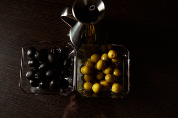 Black and green olives in glass bowls with silver oil jug