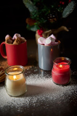 Cozy holiday scene with candles and hot chocolate on a snowy table