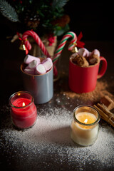 Warm holiday scene with mugs of hot cocoa and festive candles