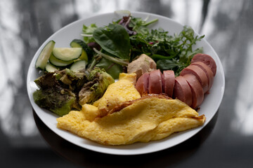 Healthy nutritious breakfast plate with herb omelette and sausage
