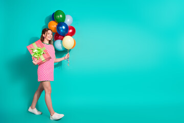 Fototapeta premium Full length photo of lovely teen lady walk hold gift air balloons dressed stylish pink plaid garment isolated on cyan color background