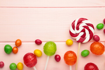 Different types of candies on pink wooden background, copy space. Colorful birthday party...