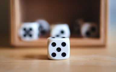 Dice laid out on a wooden table with a storage box in the background during tabletop gaming night