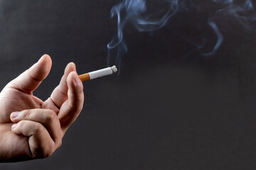 Cigarette in hand with smoke with copy space.