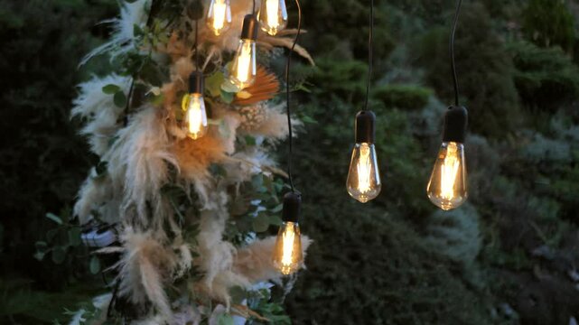 Wedding ceremony. wedding arch in boho style with garland lamps