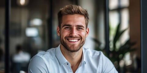 Obraz premium Portrait of a cheerful young businessman in an office setting, showcasing a smile. This happy businessman embodies positivity and professionalism in the workplace.