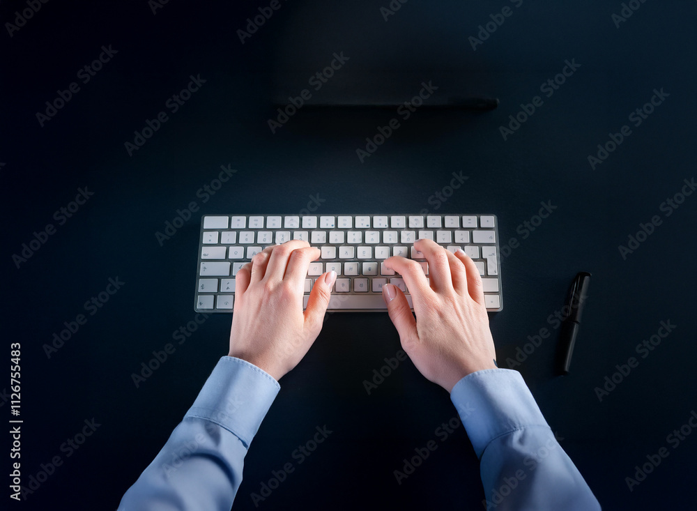 Poster overhead view of hands typing on a white keyboard at night. a pen and stylus rest nearby on a dark s