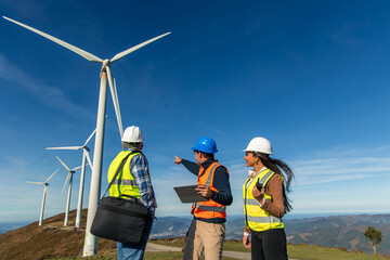 Three multiethnic Engineers working at wind turbine power plant discussing green energy production © EDER