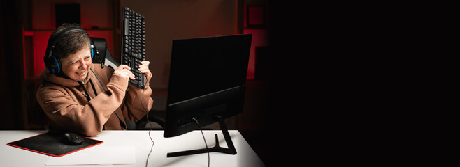 Angry aggressive angry woman in headphones about to smash keyboard defeated in game