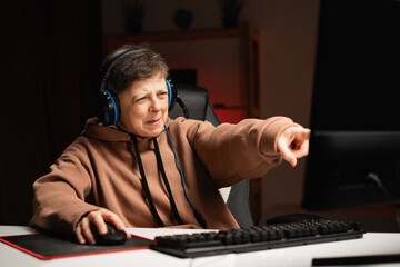 Aggressive female gamer wear headset playing online video games and pointing finger looking blaming you expressing negative emotions