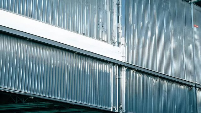 Camera zooms out to reveal a wall made of galvanized steel panels with a corrugated texture