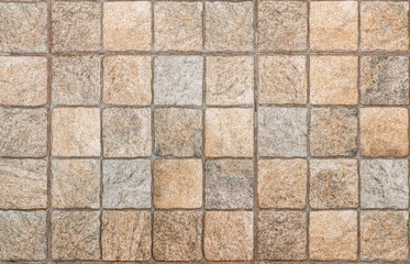 Obraz premium Beige square ceramic tiles in close-up, forming a seamless pattern ideal for interior design backgrounds and textures