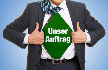 Geschäftsmann im Anzug zeigt Slogan „Unser Auftrag“ unter seinem Hemd