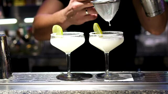 hand bartender using strainer in vodka coconut smooth fizzy cocktail at luxurious counter preparation making special to guest at fronted bar. Special refresh showcasing nightlife. Vinosity.