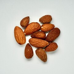 Pile of brown almonds isolated on square white background from above angle view.