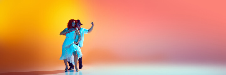 Banner. Couple dancer share their feeling throw salsa moves in neon light against gradient orange...
