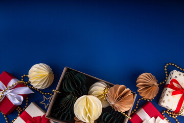 Christmas flat lay background in cozy nordic hygge style, Composition with traditional Scandinavian paper honeycomb ornaments, gift boxes, golden garland. Modern trendy eco Christmas decor