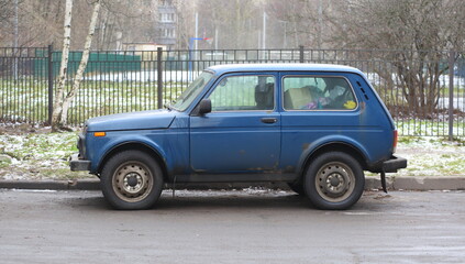 Fototapeta premium Old blue short-wheelbase Russian jeep with rust spots, Iskrovsky Prospekt, Saint Petersburg, Russia, December 10, 2024