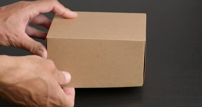Hands opening an empty cardboard box for storage or packaging purposes. 