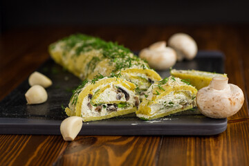 baked potato roll with cottage cheese filling with garlic and mushrooms, on a dark wooden table