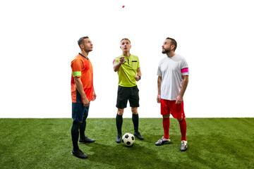 Referee standing between to players from opposite teams and tossing a coin to determine which team...