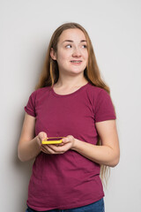 Young beautiful girl uses modern smartphone at home