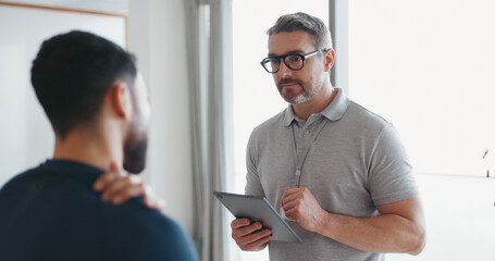 Physiotherapy, tablet and shoulder pain with man and athlete in clinic for rehabilitation,...