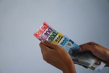 Filipino peso held in hand, showcasing the banknotes and coins as a symbol of local currency and...
