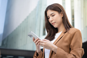 Asian business woman utilizing phone for digital remote work in urban setting