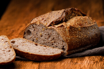 Sliced ​​rustic sourdough bread on wooden table on black background
