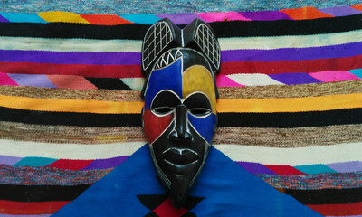 Gabonese wooden mask matches the colors and patterns of a Tunisian Amazigh Margoum carpet. The...