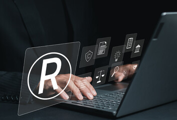Businessman working on laptop with digital icons register trademarks, copyright, patent, intellectual property law, legal protection in business.