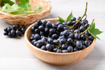 Black grapes in wooden bowl on white table, Seedless grapes