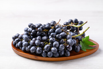 Black grapes on wooden plate with white table, Seedless grapes