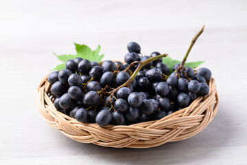 Black grapes in basket on white table, Seedless grapes
