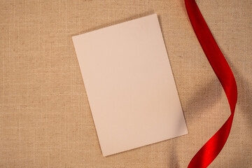 Blank paper with red ribbon on side, Aesthetic beige flat lay background, Season's greetings background with ribbon, Horizontal background stock image