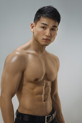 Fototapeta premium Portrait of a shirtless muscular Asian man with defined abs and a confident gaze, showcasing his toned physique. Perfect for fitness, health, and modern lifestyle promotional themes. 