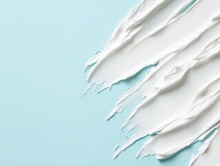 Creamy skincare product textures with smooth strokes on a light blue background, half space for text.