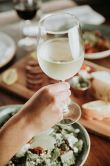 Person Holding a Glass of White Wine at a Dinner Table