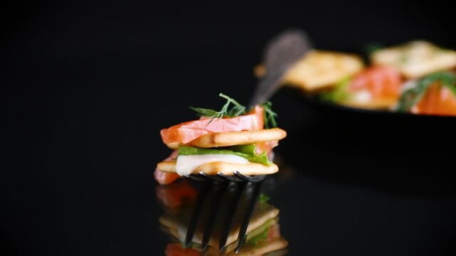 small snack canapes with crackers and lightly salted red fish Salmon, isolated on black background.