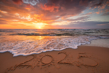 Happy New Year 2025 concept, lettering on the beach. Written text on the sea beach at sunrise.